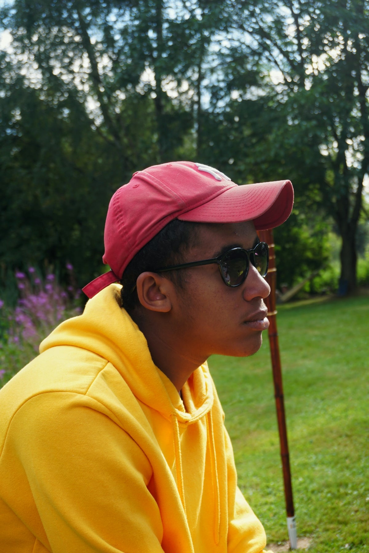 man in yellow hoodie wearing black sunglasses and red cap