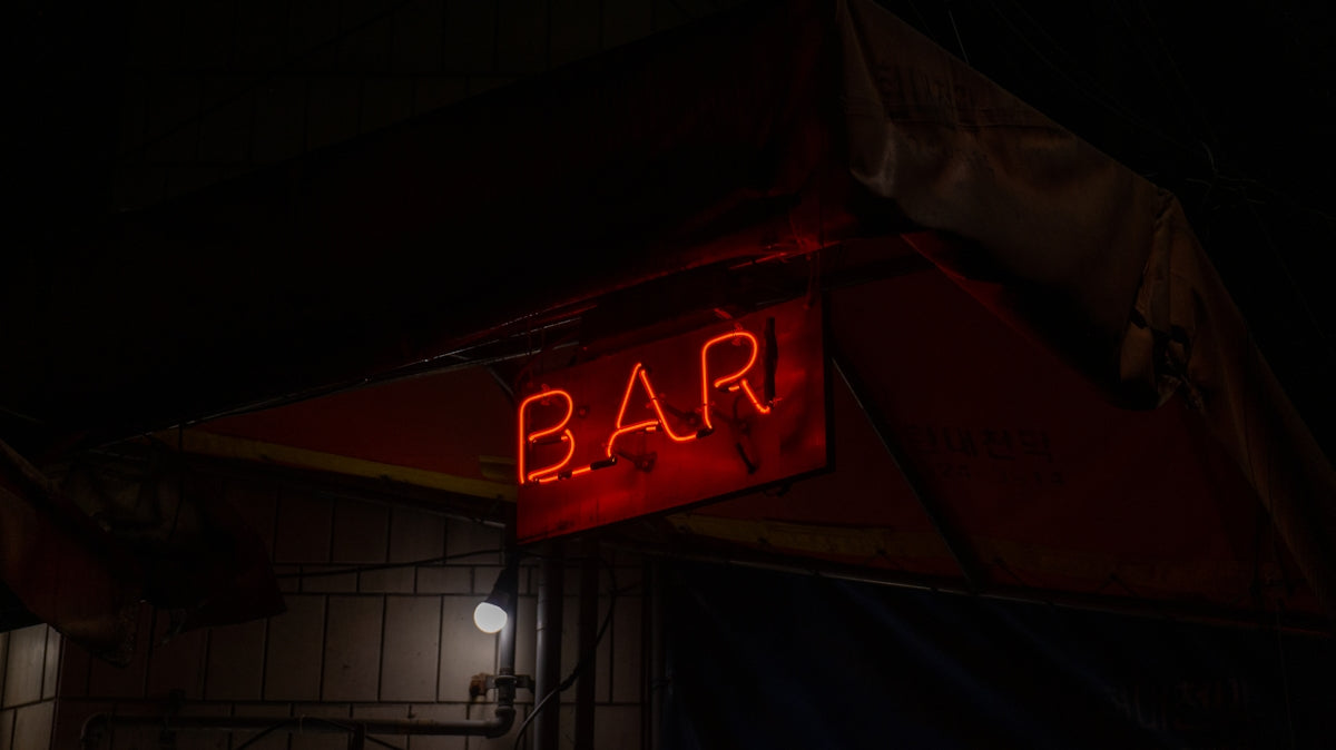 a red neon sign that says bar on it