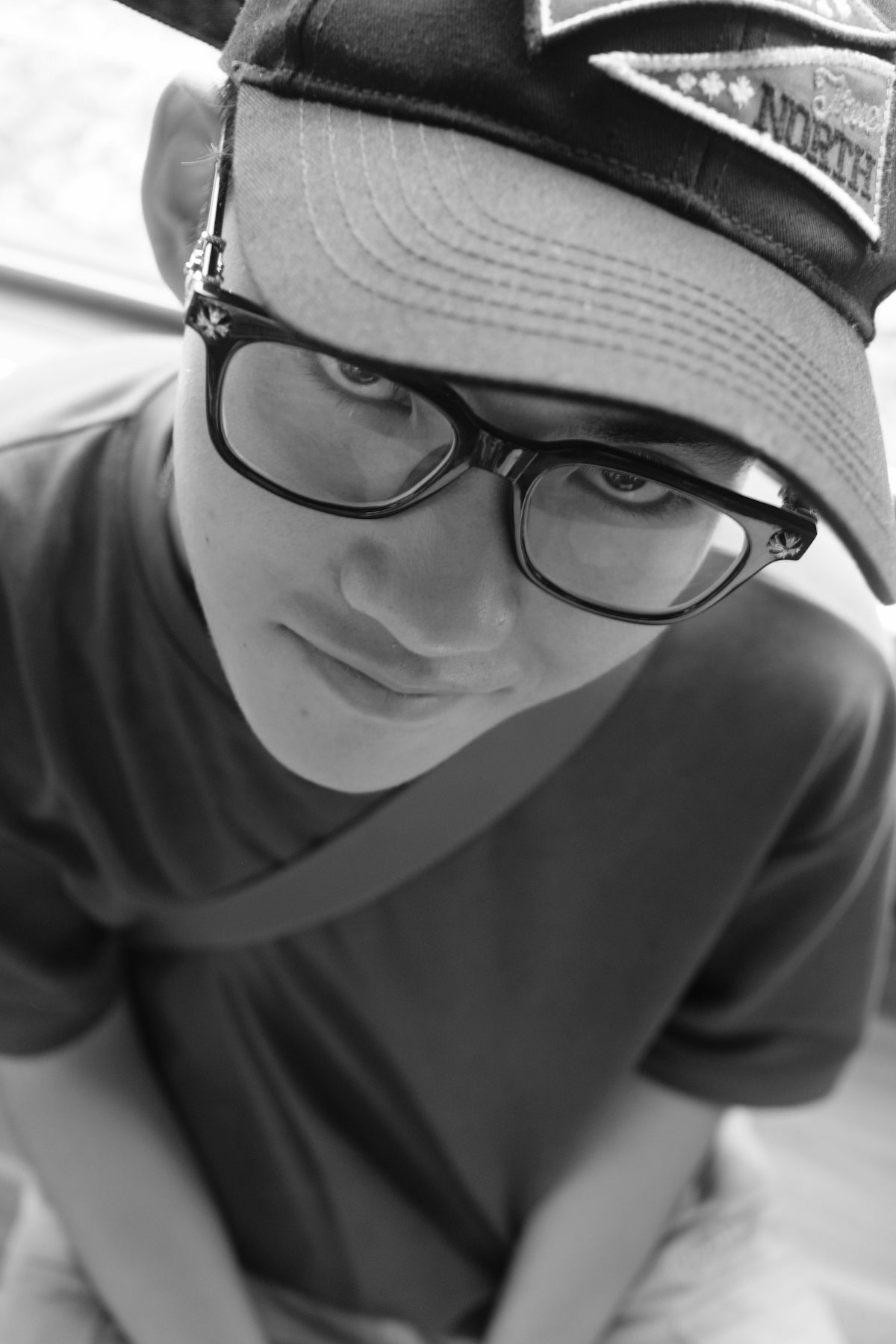 A boy wearing a hat and glasses holding a cat