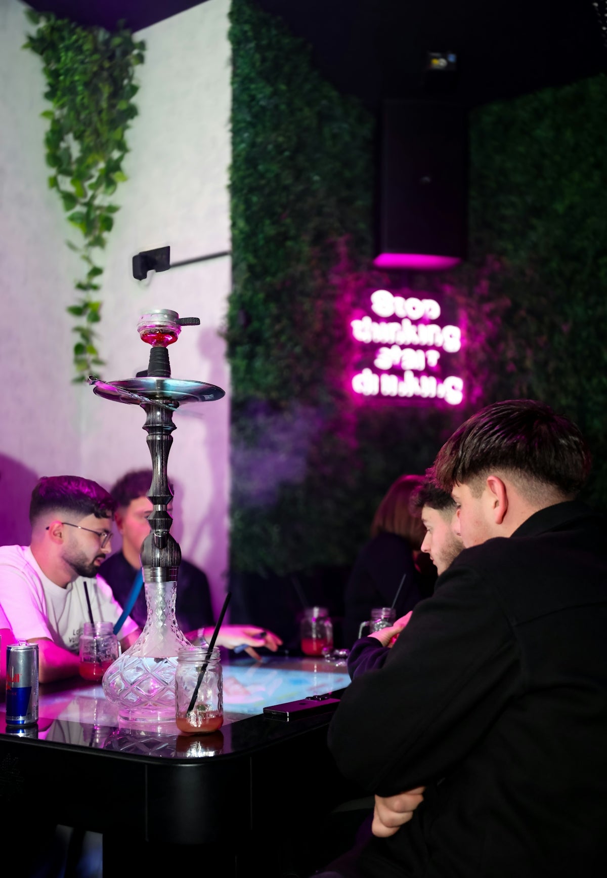 People gathered around a table with a hookah pipe.
